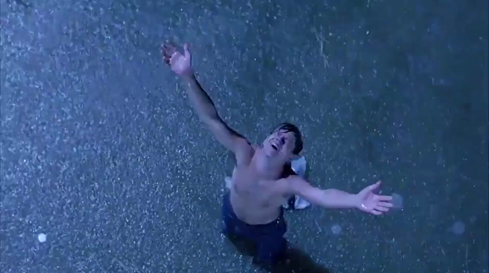 a man is standing in the rain with his arms outstretched