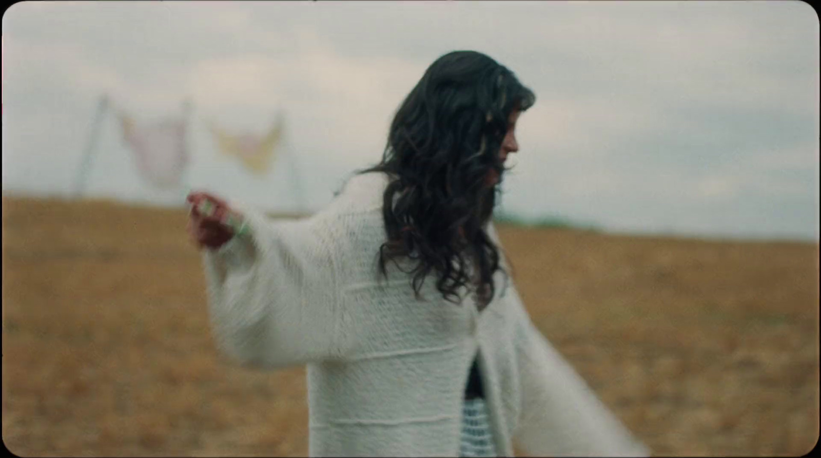 a man with long hair holding a kite in a field