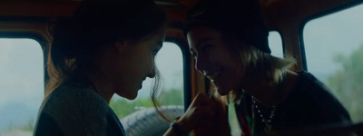 two young women sitting in the back of a bus