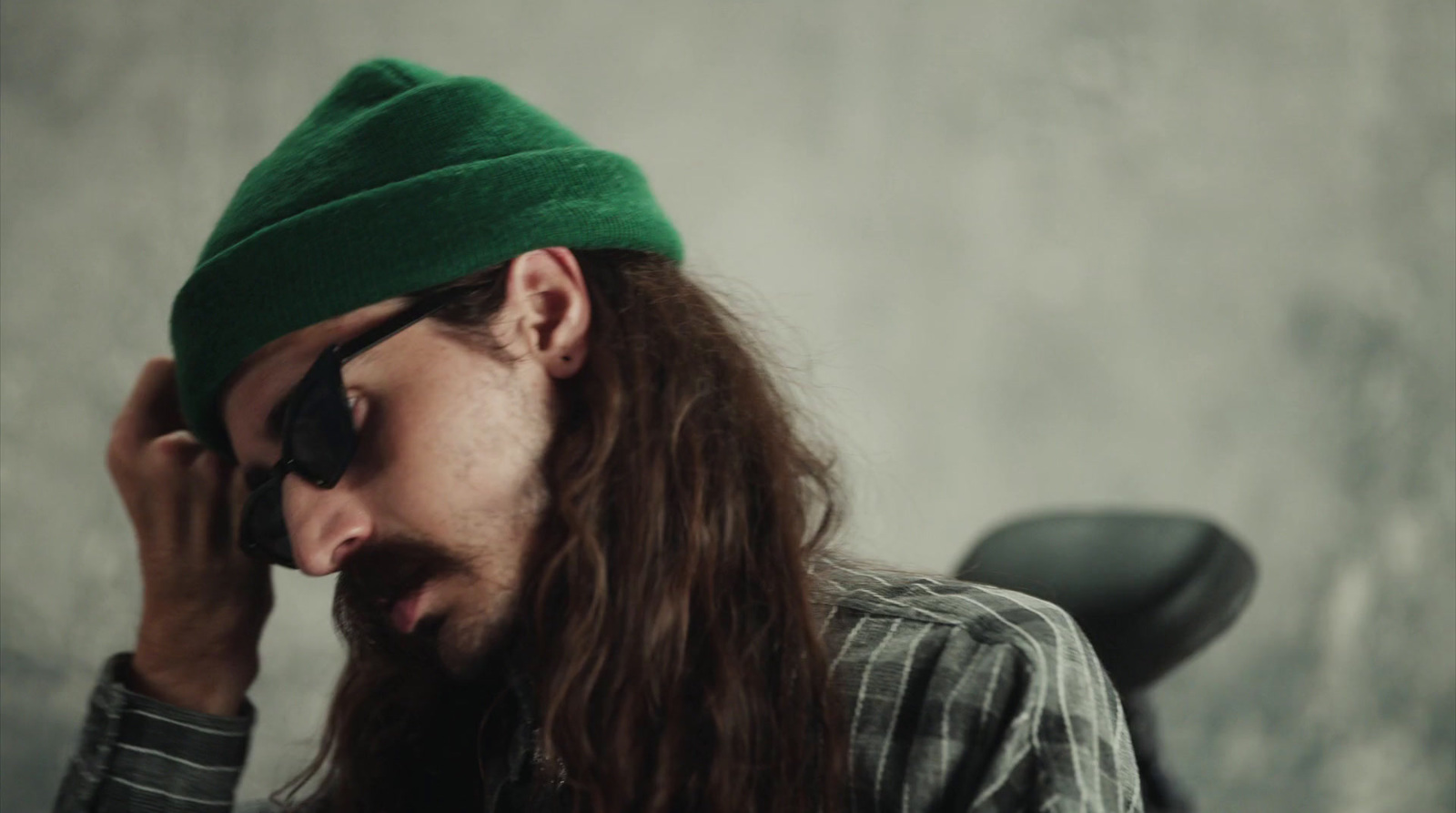 a man with long hair wearing a green hat