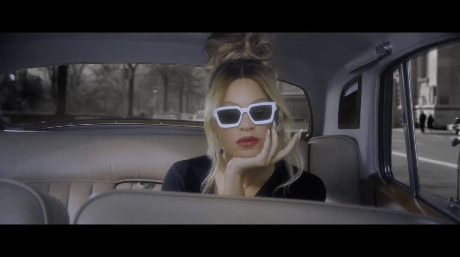 a woman in sunglasses sitting in the back seat of a car