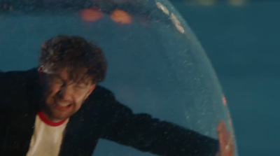 a man in a black suit and white shirt in a bubble