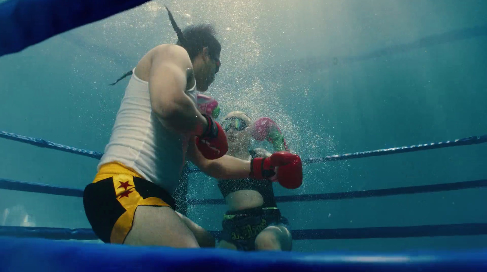 a man in shorts and a tank top boxing under water