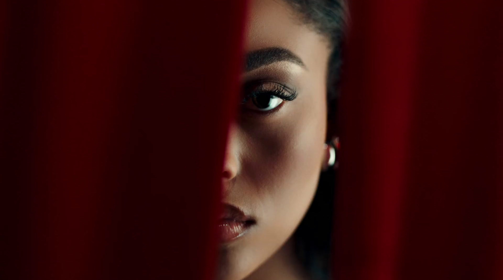 a woman looking through a red curtain