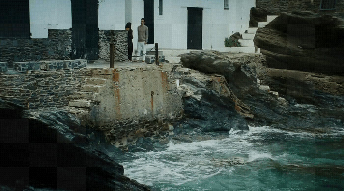 a man standing on the edge of a cliff next to a body of water