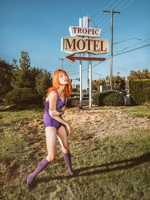 a woman in a purple outfit is posing in front of a sign