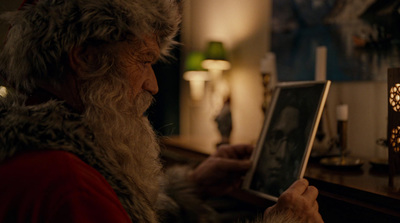 a man dressed as santa claus holding a tablet