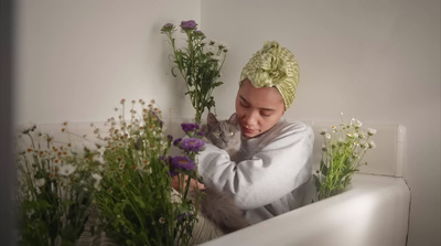 a woman with a cat in a bathtub surrounded by flowers