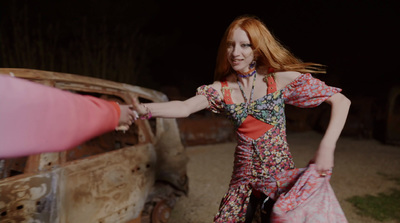 a woman in a floral dress holding onto a pink object