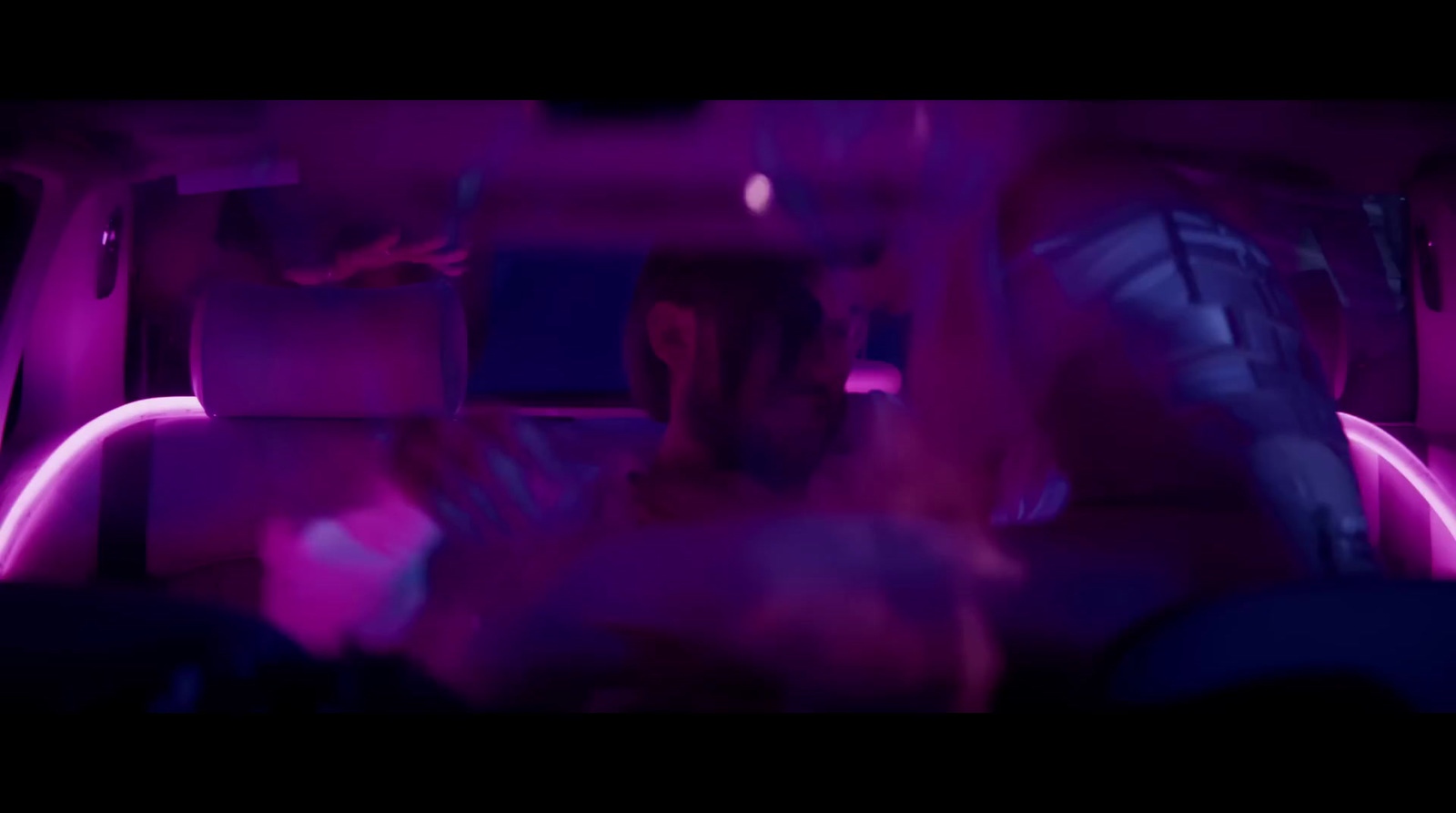 a group of people sitting in a car with purple lights