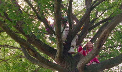 a young girl sitting in a tree with her feet up