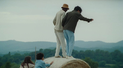 a couple of people standing on top of a hay bale