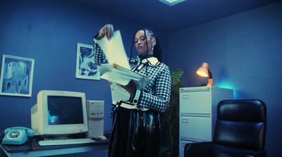 a woman standing in front of a computer holding a piece of paper