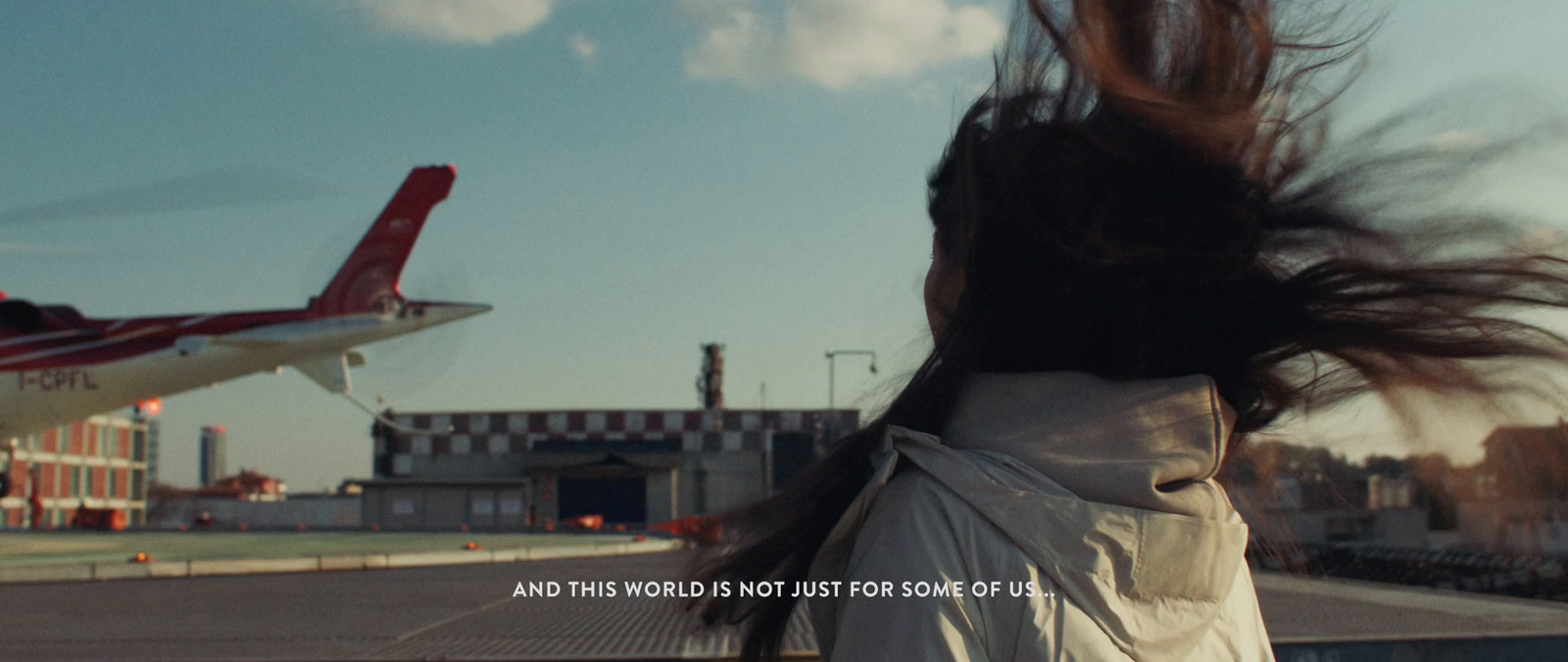 a woman standing in front of an airplane with her hair blowing in the wind