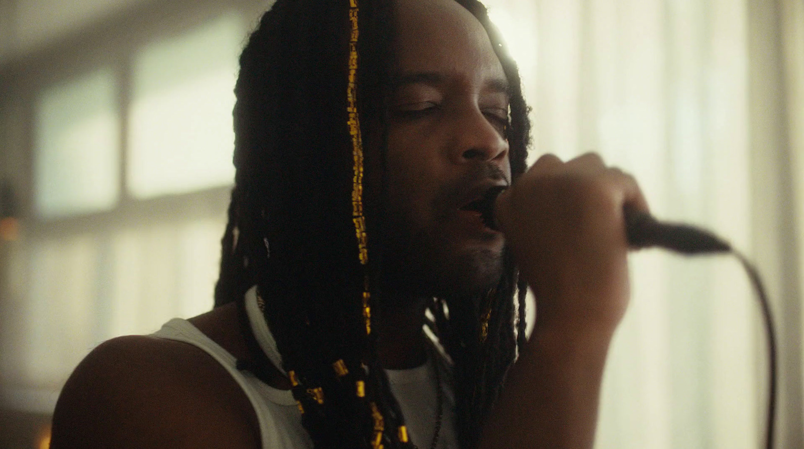 a man with dreadlocks singing into a microphone