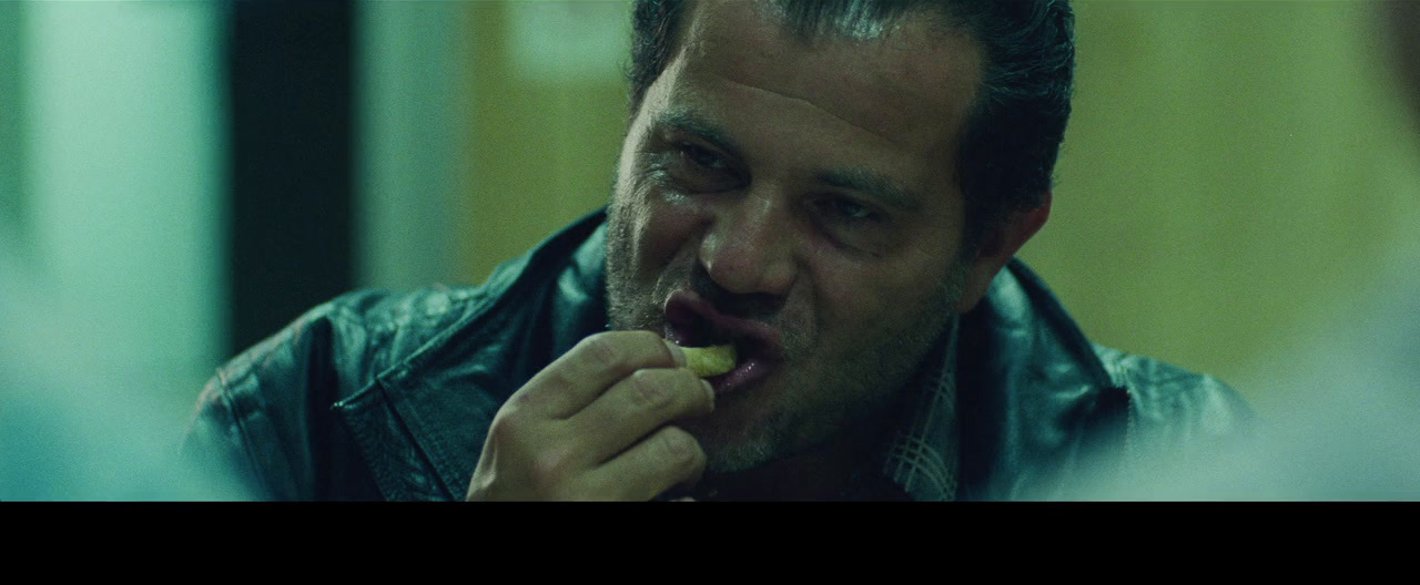 a man in a leather jacket eating a piece of food