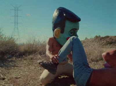 a person sitting on the ground with a mask on