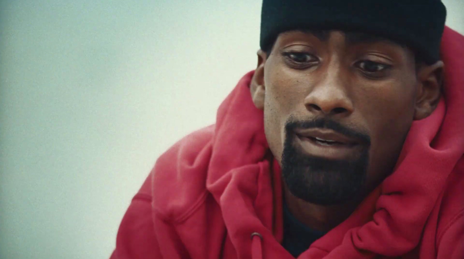 a man wearing a red hoodie and a black cap