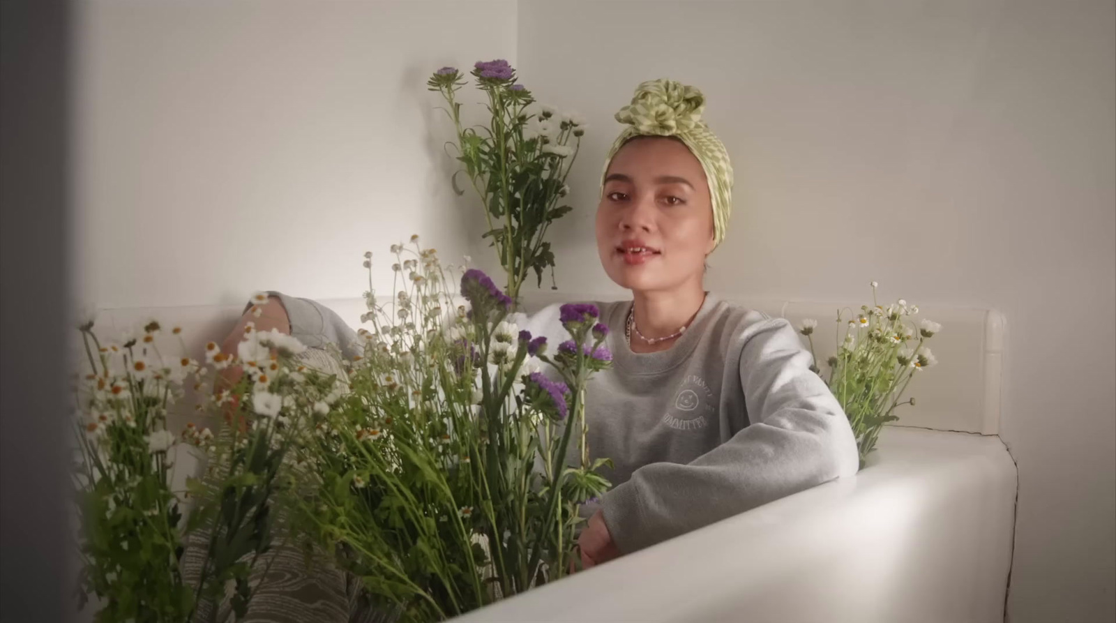 a woman sitting in a bathtub next to a bunch of flowers