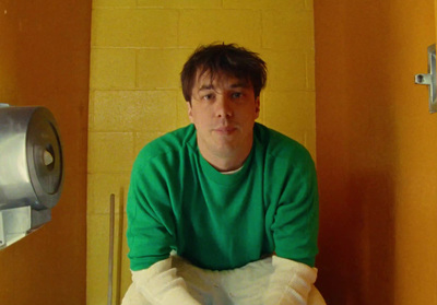 a man in a green shirt sitting on a toilet