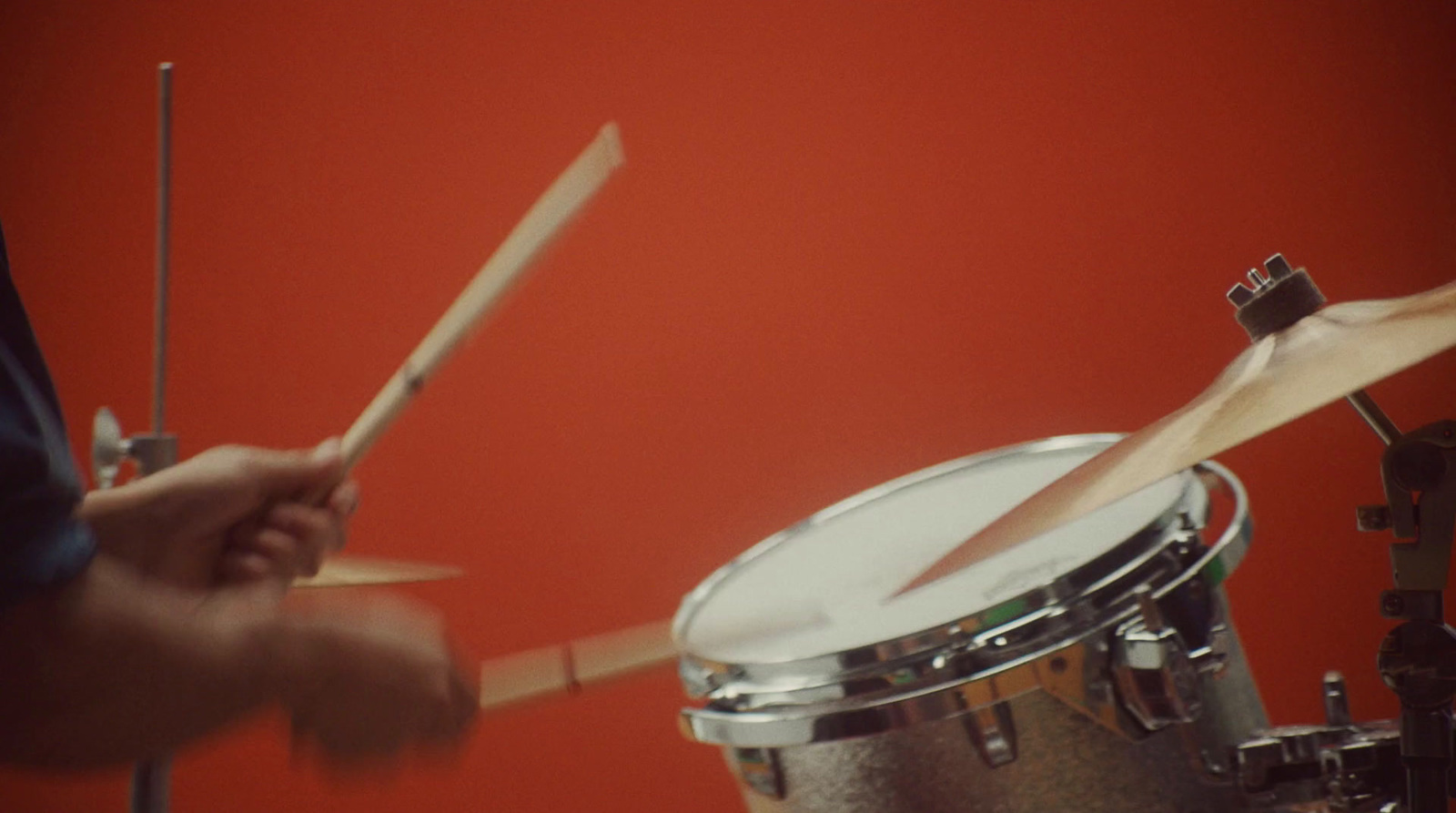 a person playing drums in a room with red walls