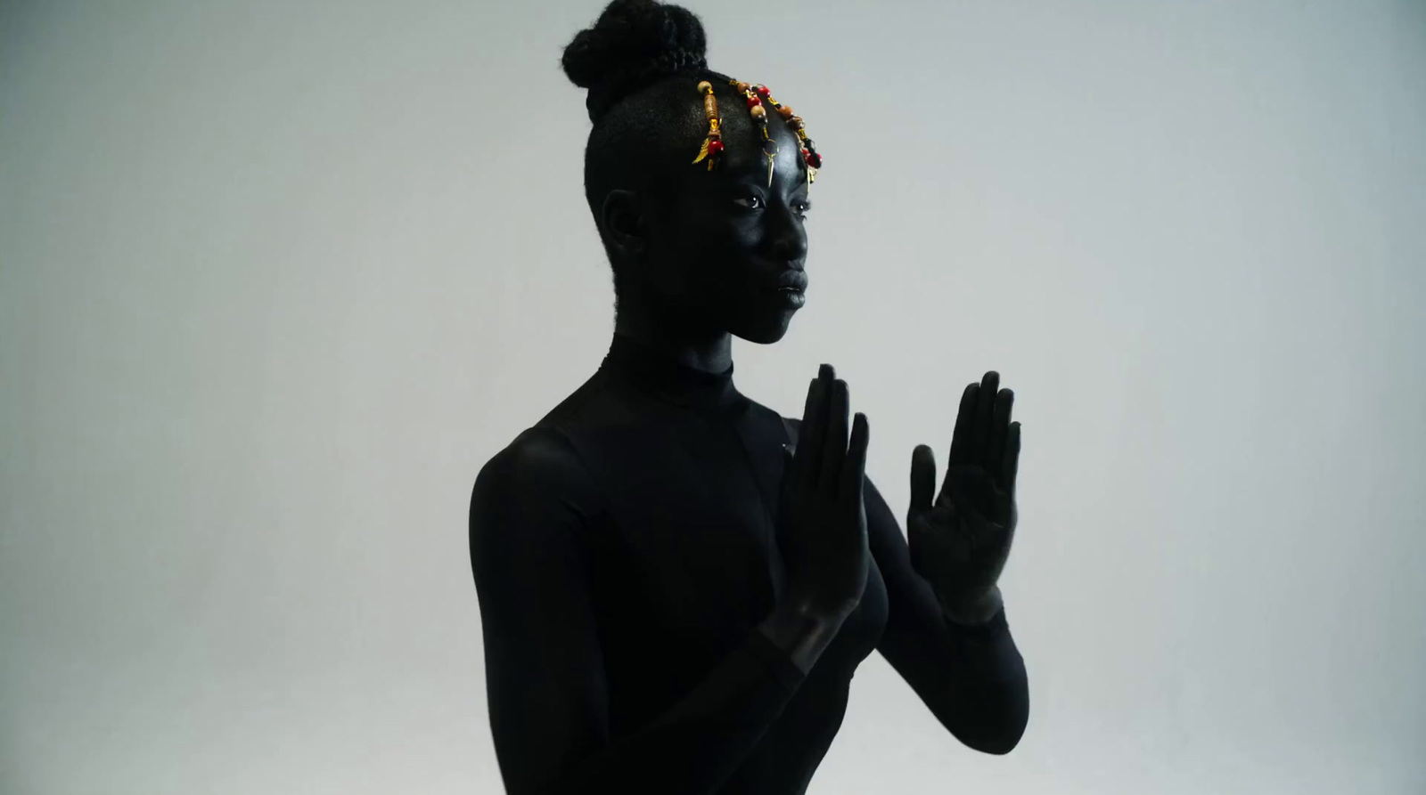 a woman in a black bodysuit with her hands in the air