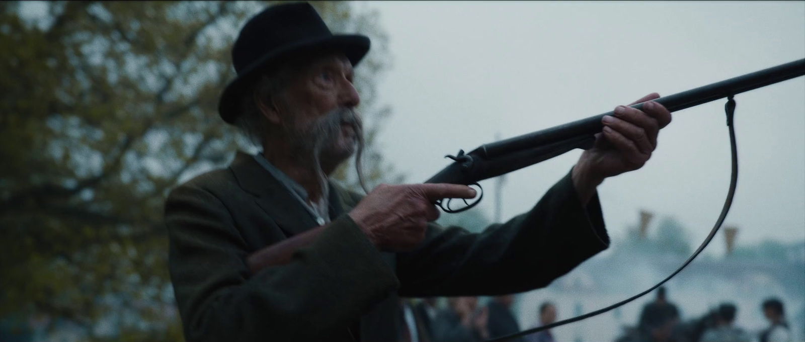 a man holding a rifle while wearing a hat