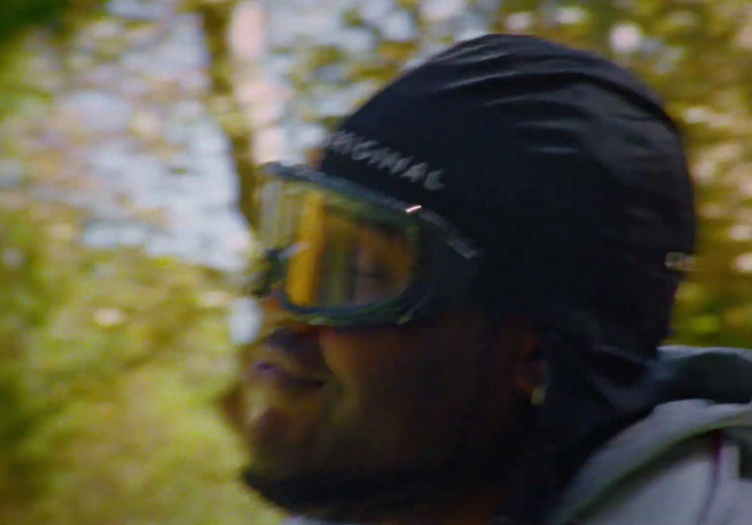 a man wearing goggles and a jacket in the woods