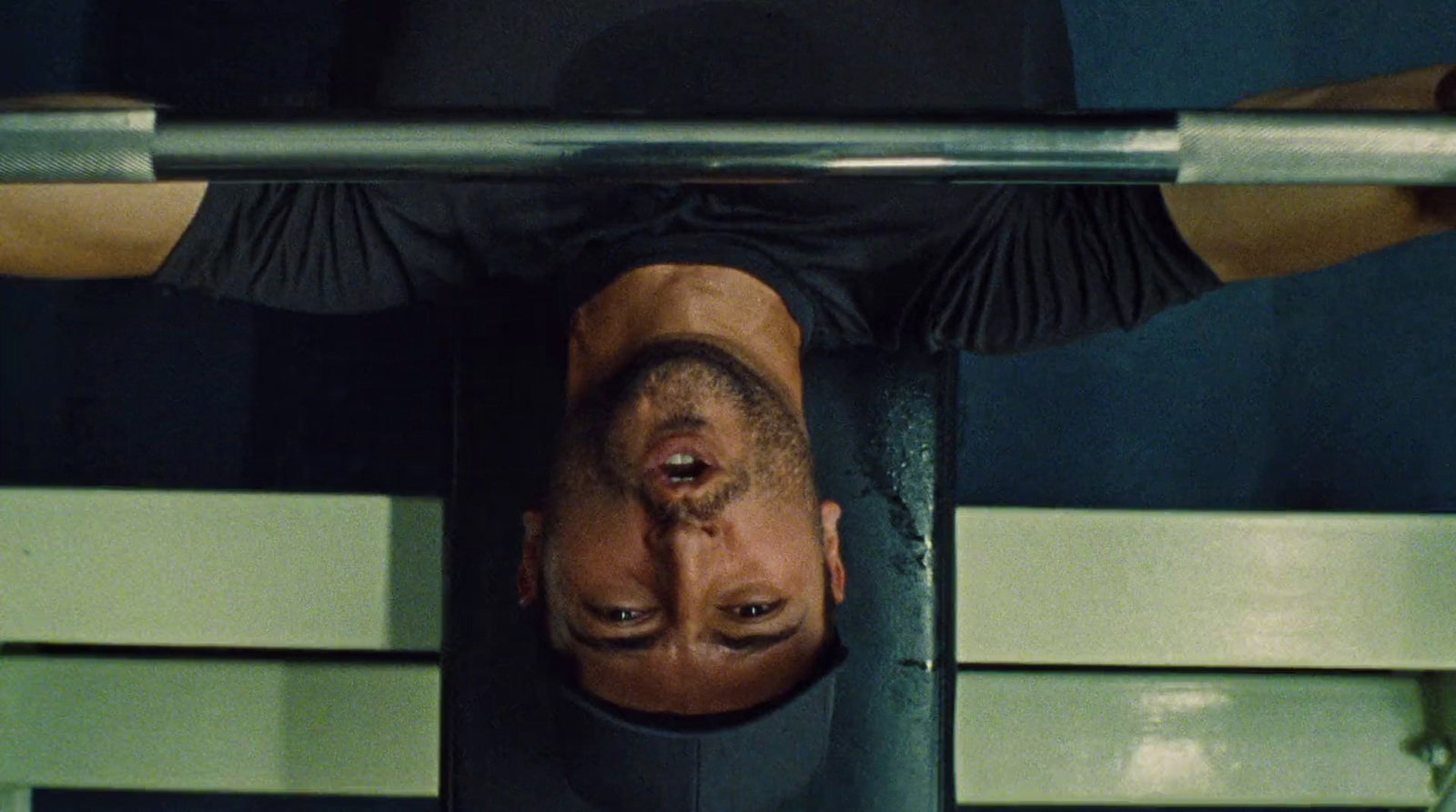 a man in a black shirt is hanging upside down on a bar