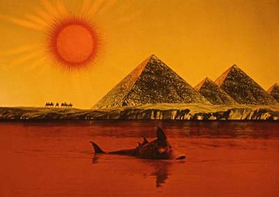 a painting of a man swimming in the water with pyramids in the background