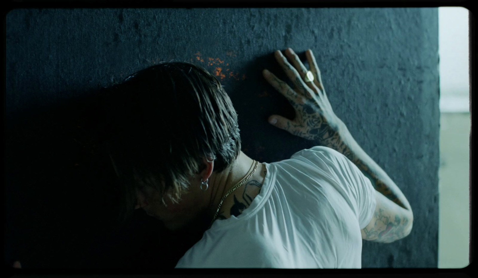 a man with tattoos on his arm leaning against a wall