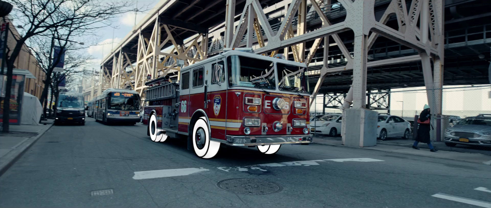 a red fire truck driving down a street next to a tall building