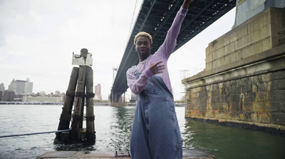 a man in overalls standing in front of a bridge