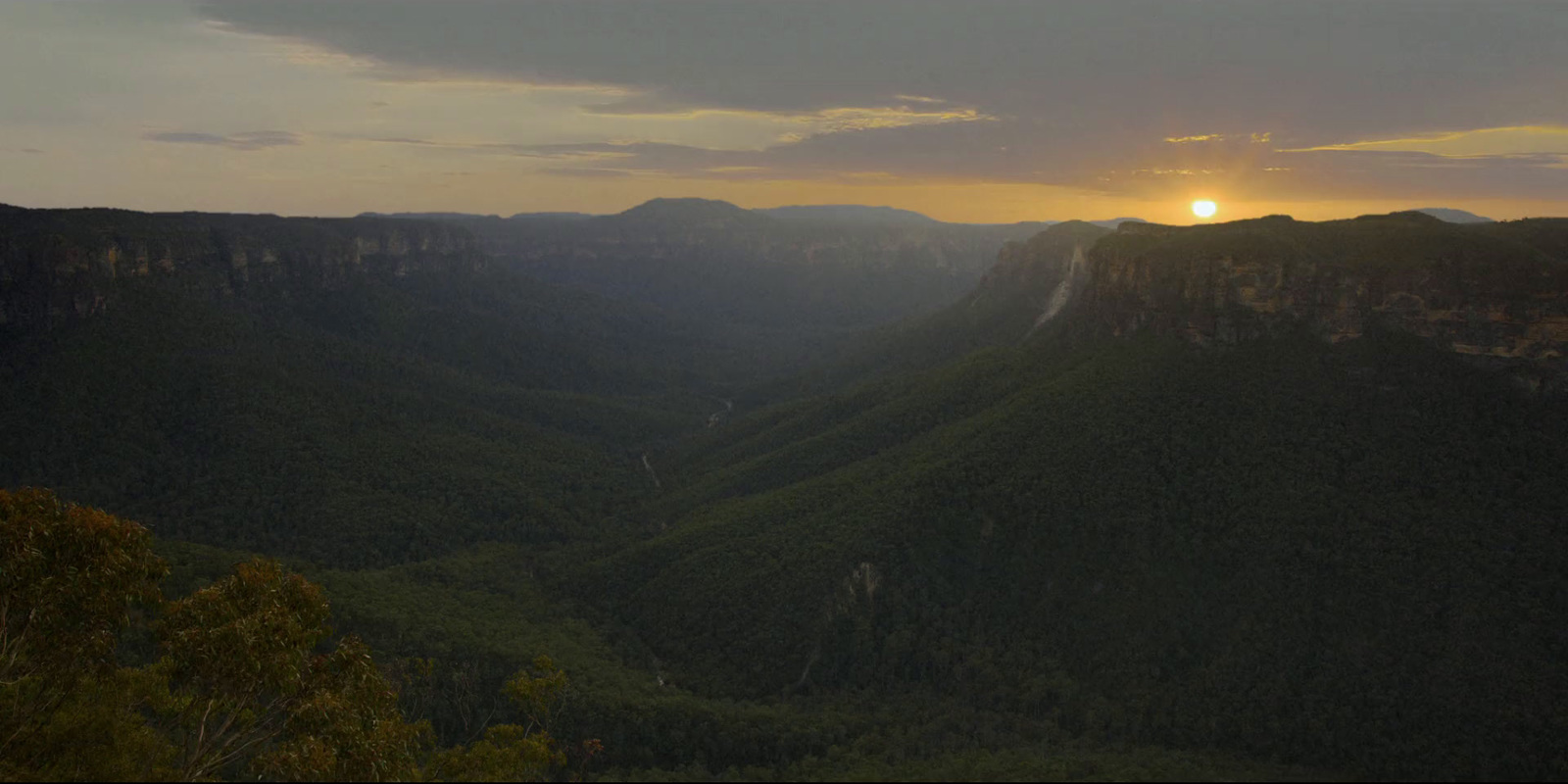 the sun is setting over the mountains in the distance