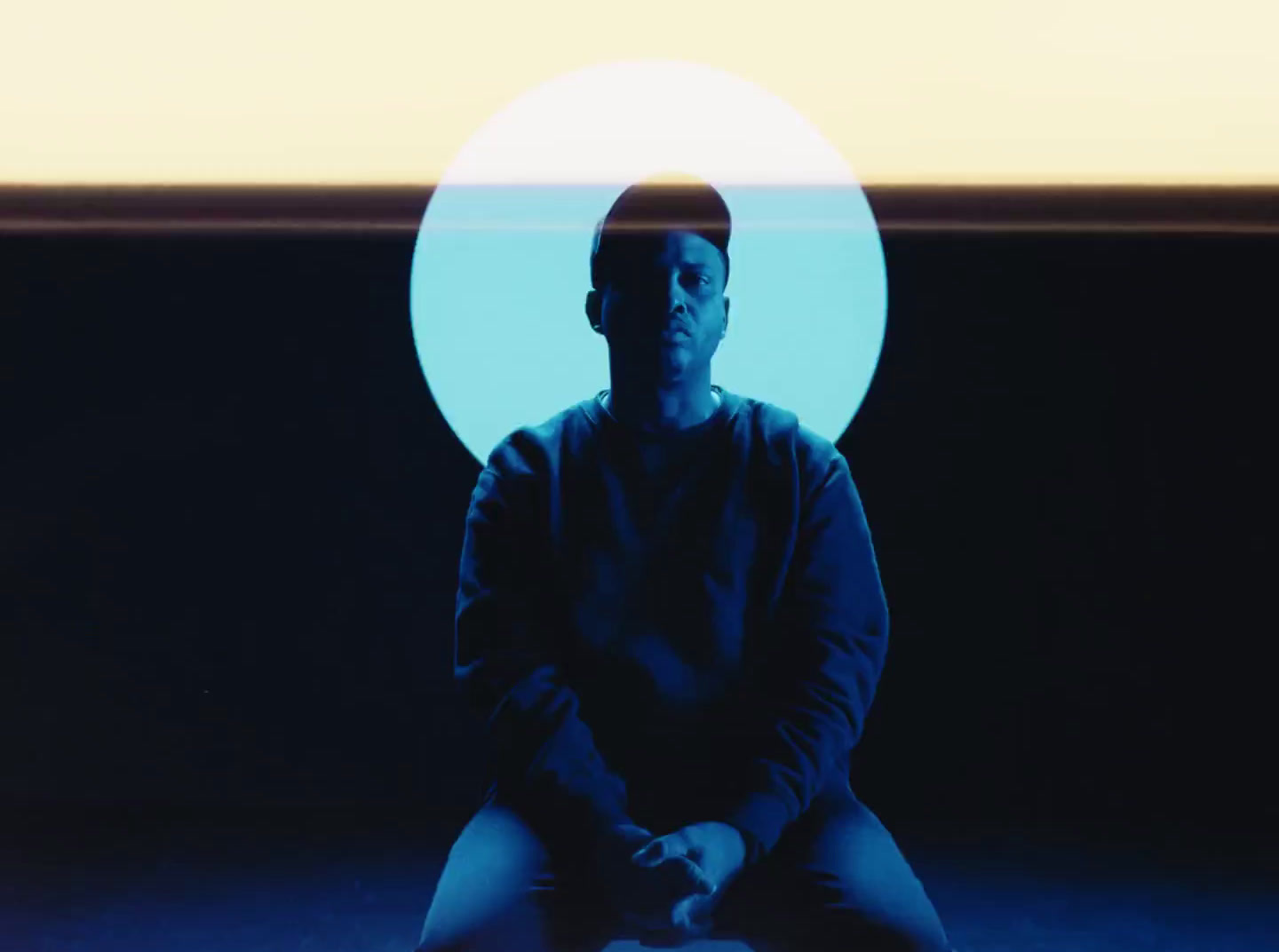 a man sitting on a stool in front of a blue background