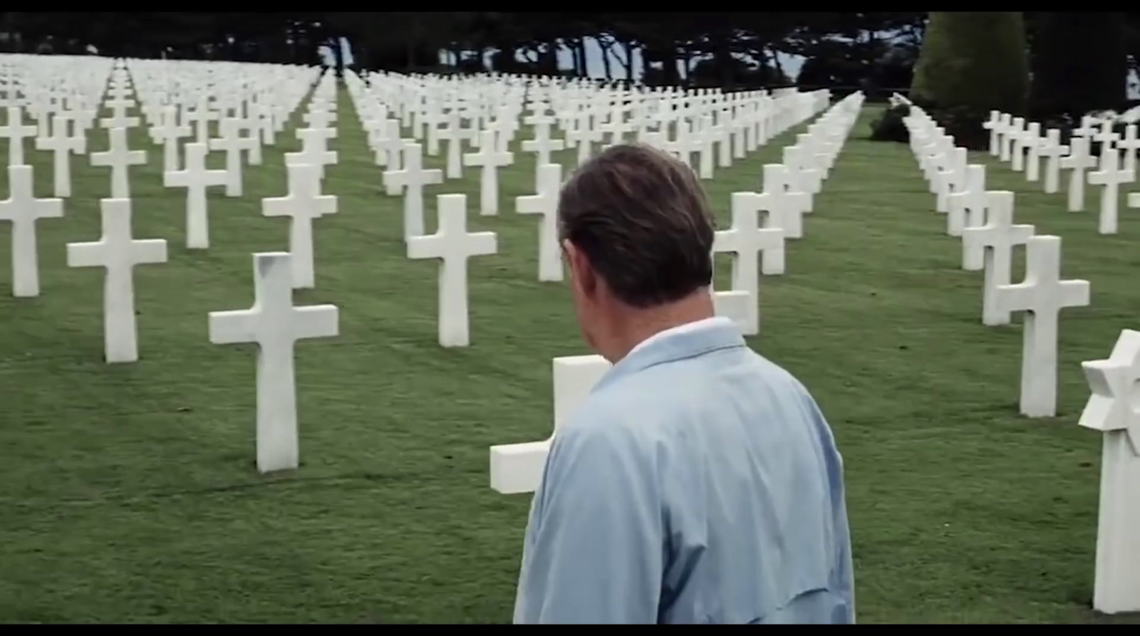 a man standing in front of a field of crosses