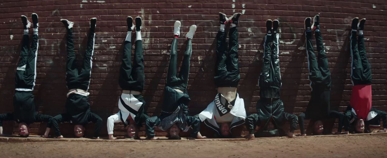 a group of people doing a handstand in front of a brick wall