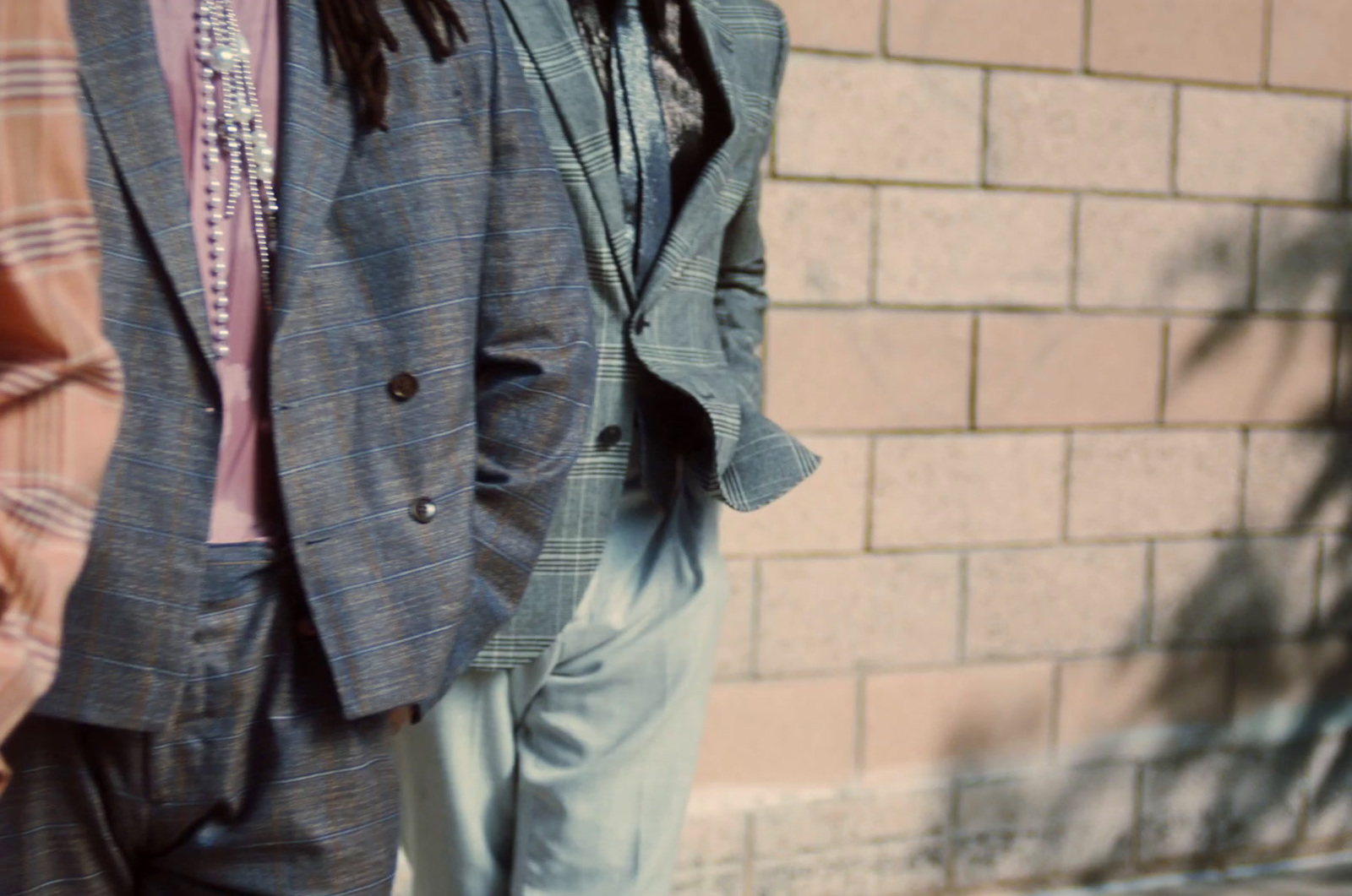 a man in a suit and tie standing next to a brick wall