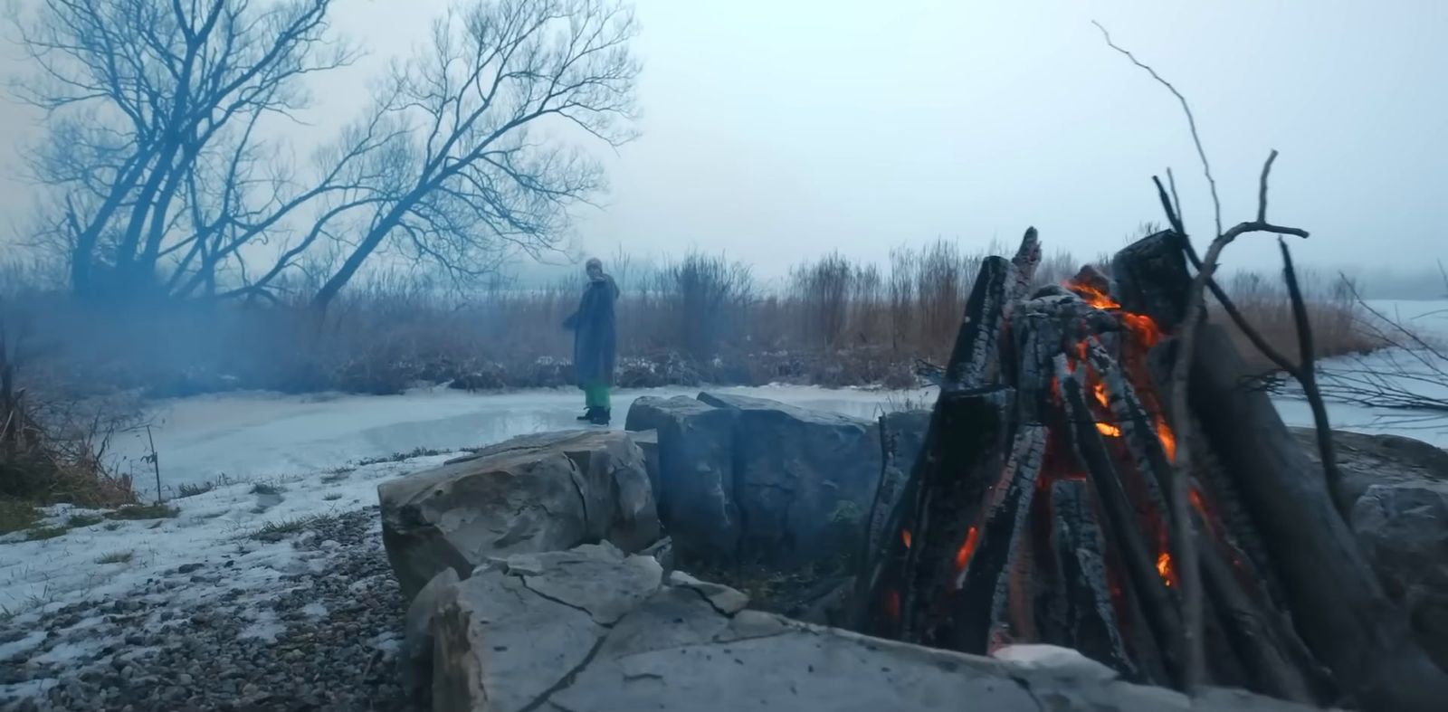 a man standing next to a pile of logs