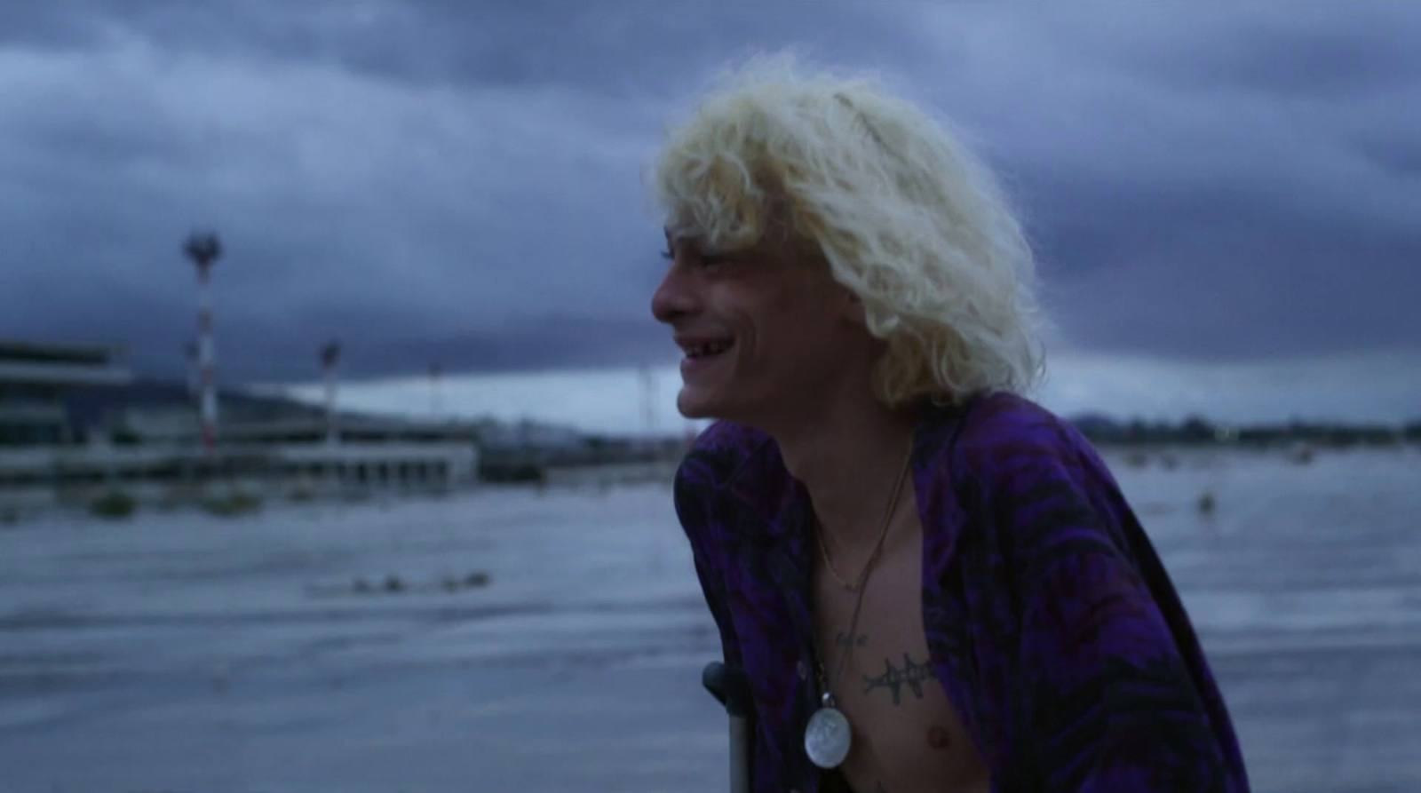 a man with blonde hair standing on a beach