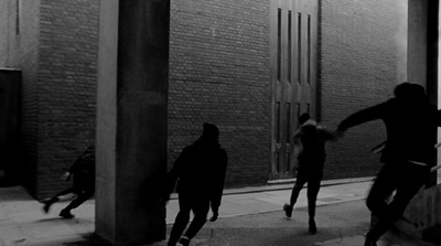 a group of people walking down a street next to tall buildings