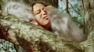 a woman laying in a tree with her eyes closed