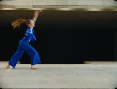 a woman in a blue jumpsuit is dancing