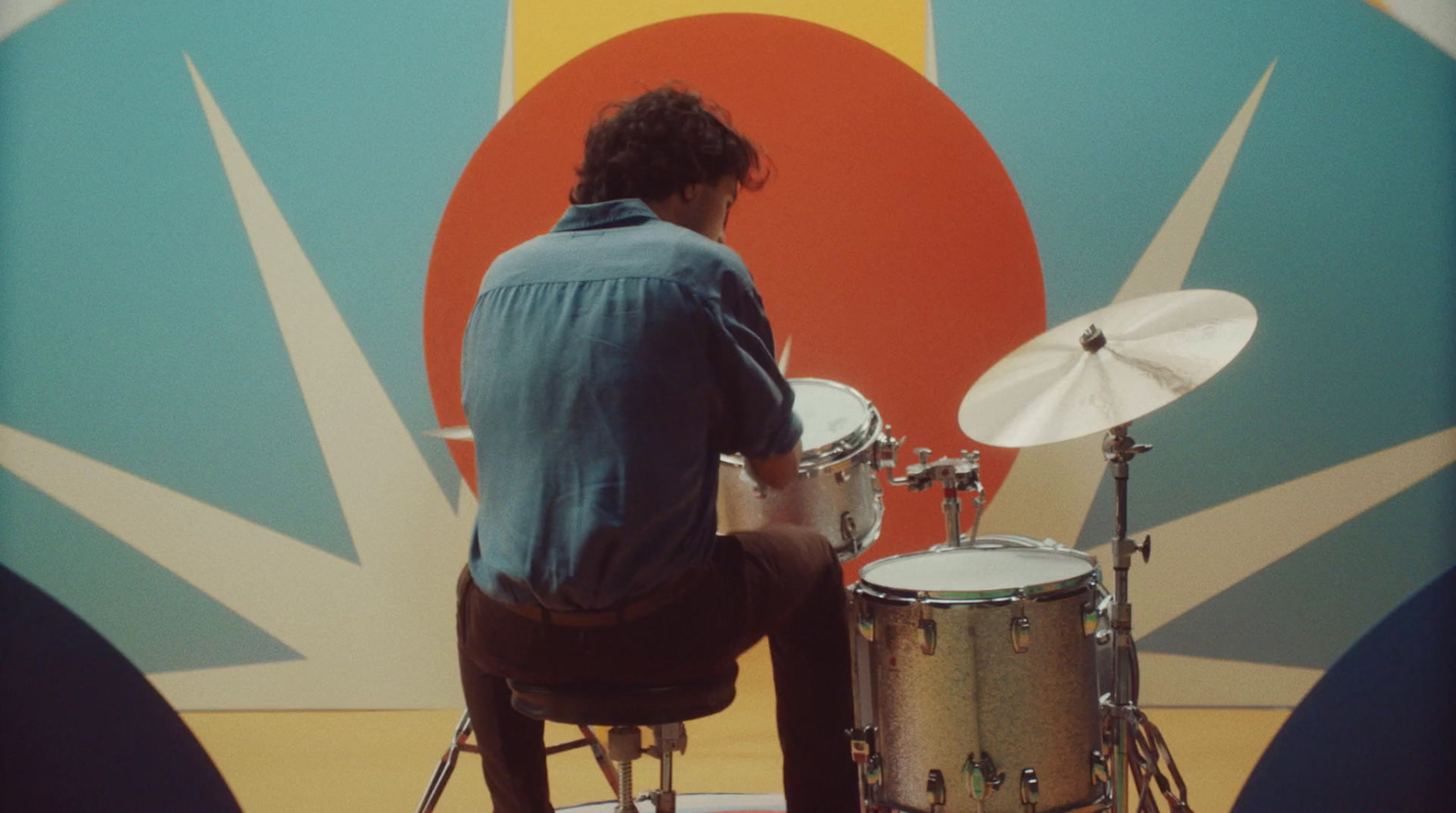 a man sitting on a stool playing drums