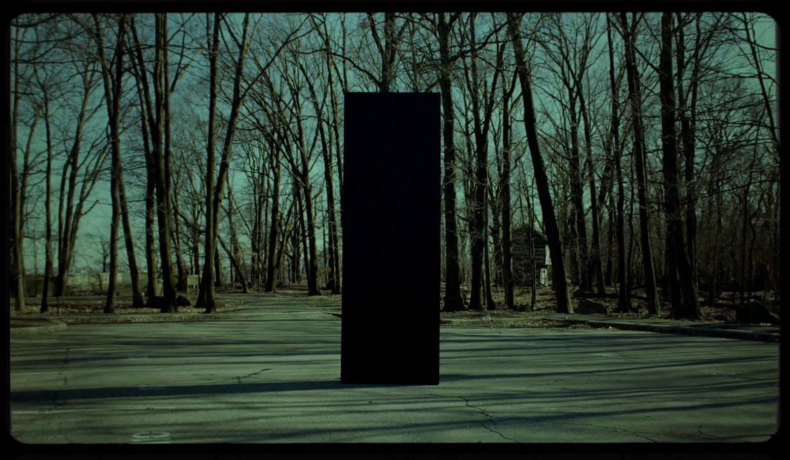 an empty parking lot with trees in the background