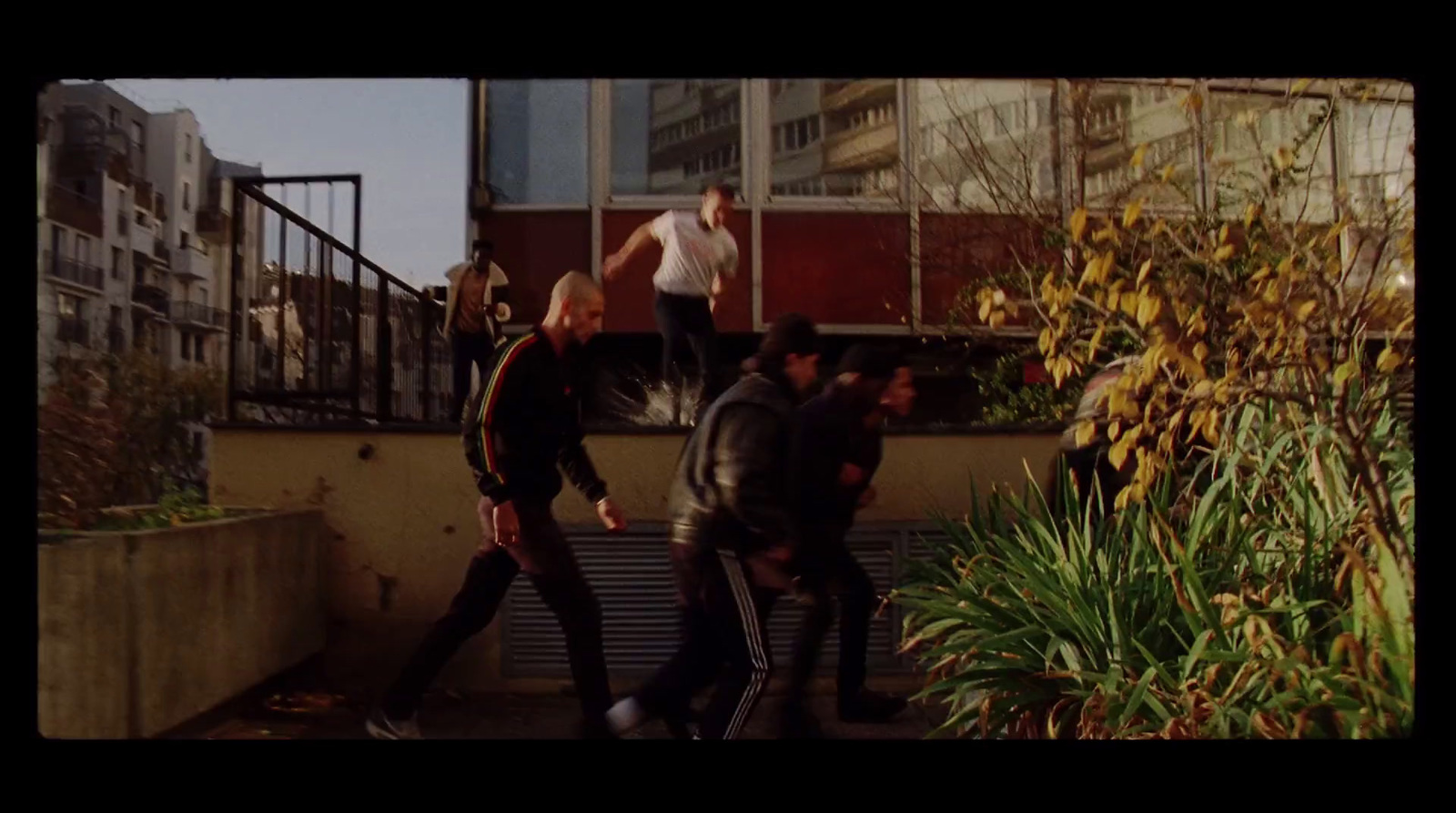 a group of men walking down a sidewalk next to a building