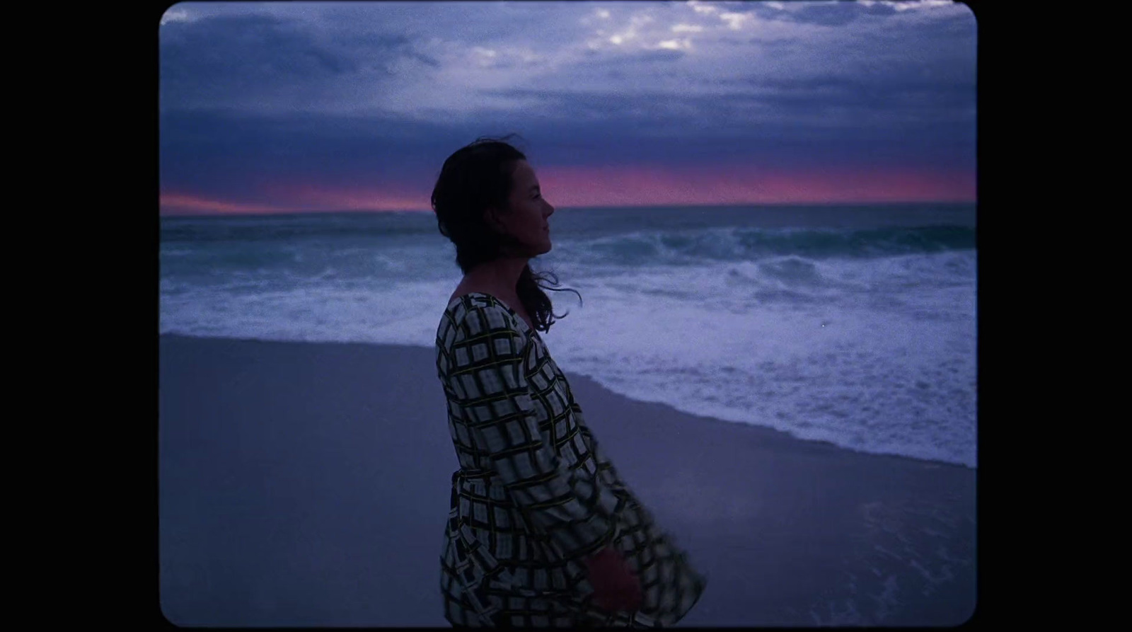 a woman standing on a beach next to the ocean