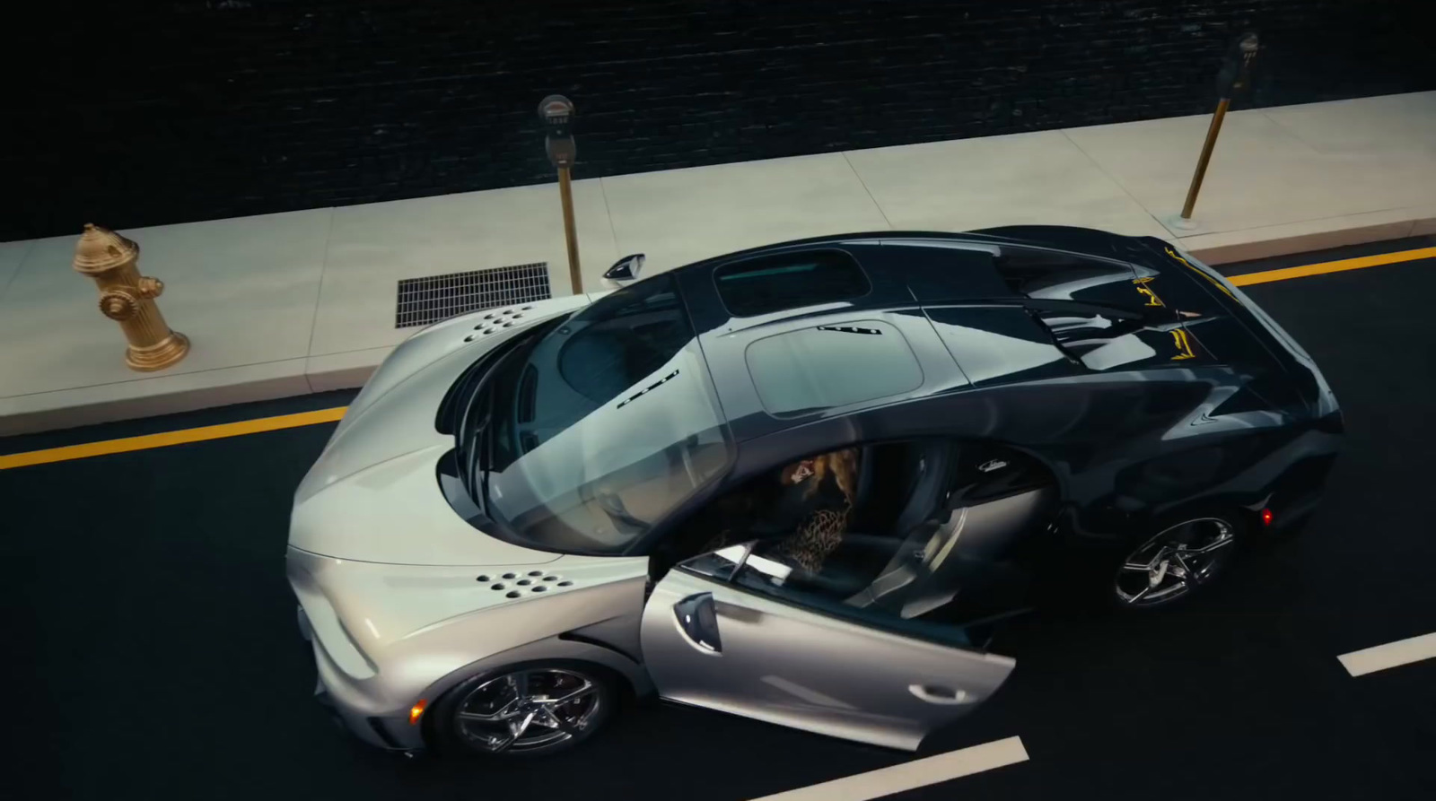 a silver sports car driving down a street next to a fire hydrant