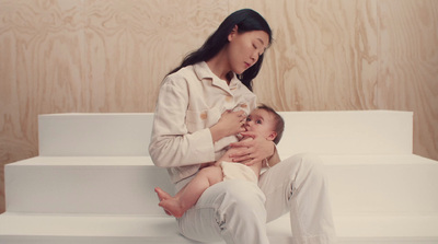 a woman holding a baby sitting on top of a white bench