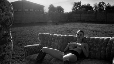 a woman sitting on top of a couch in a field